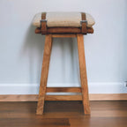 Artisan strapped bar stool with wooden legs and black leather seat, modern design, shown from front view.