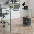 Amalfi clear glass curved desk styled in a modern home office with a laptop, lamp, and desk chair on a herringbone floor