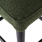 Macro shot showing the plush green seat cushion texture and dark wooden leg finish.