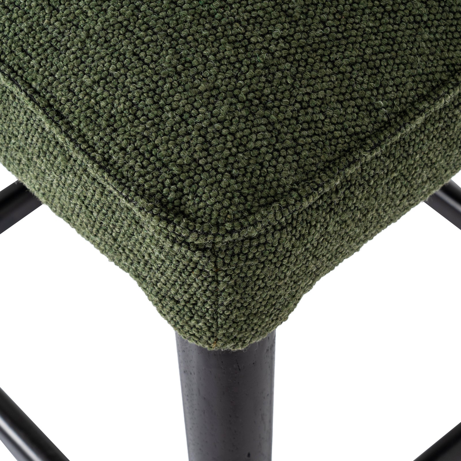 Macro shot showing the plush green seat cushion texture and dark wooden leg finish.