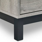 Close-up view of the black metal leg and lower frame border on the Bali grey oak chest of drawers