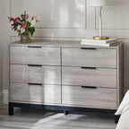 Bali grey oak effect 6 drawer wide chest styled in a bright, modern bedroom with flowers and a lamp