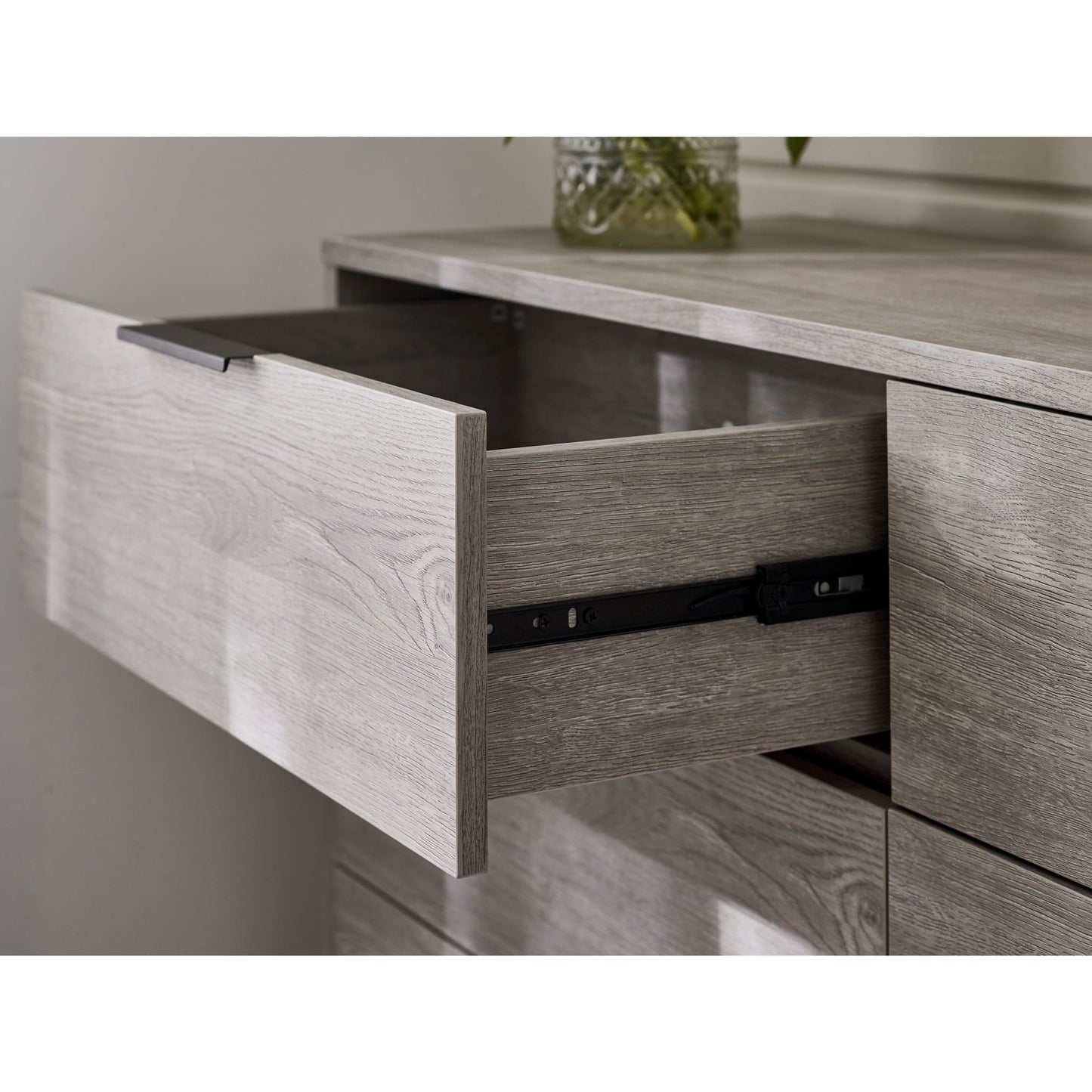 Detail shot of an open drawer highlighting the metal runner mechanism and internal storage depth on the Bali grey chest