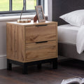 Bali natural oak effect 2 drawer bedside table styled next to a bed with a lamp and photo frame