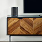 Close-up shot of the wood chevron cabinet doors and black top surface with a speaker and TV base.