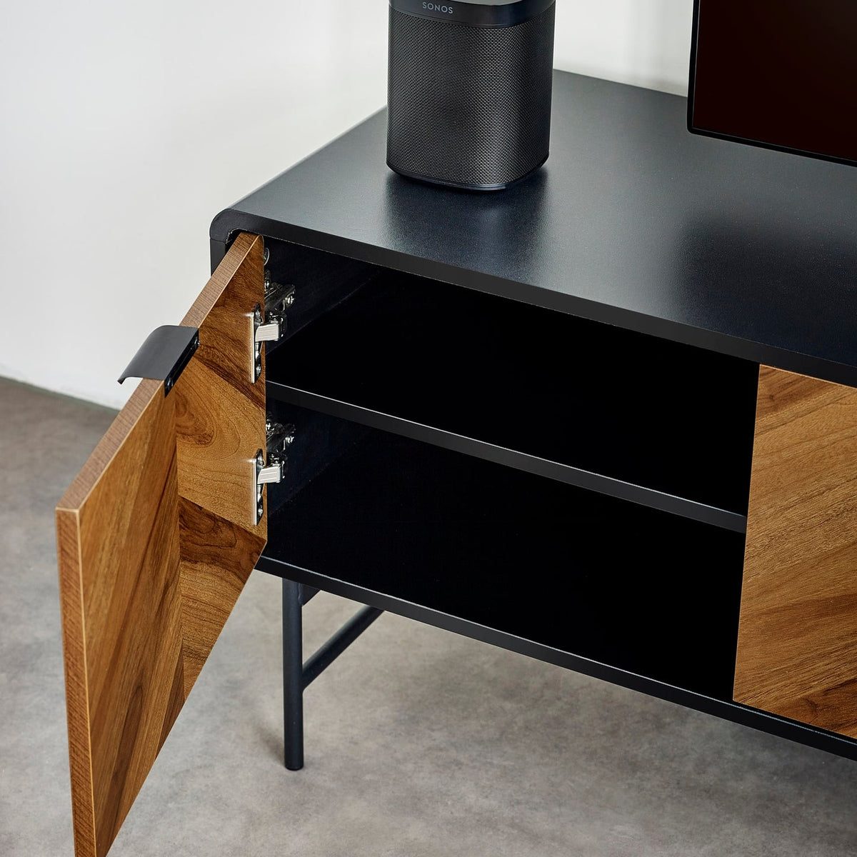 Angle view of an open wood chevron cabinet door showing interior shelf storage and hinges.