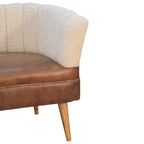 Side profile detail of the cream bouclé backrest and brown leather seat with tapered wooden legs.