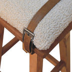 Close-up detail of the metal buckle strap and leather trim wrapped over the soft bouclé seat.