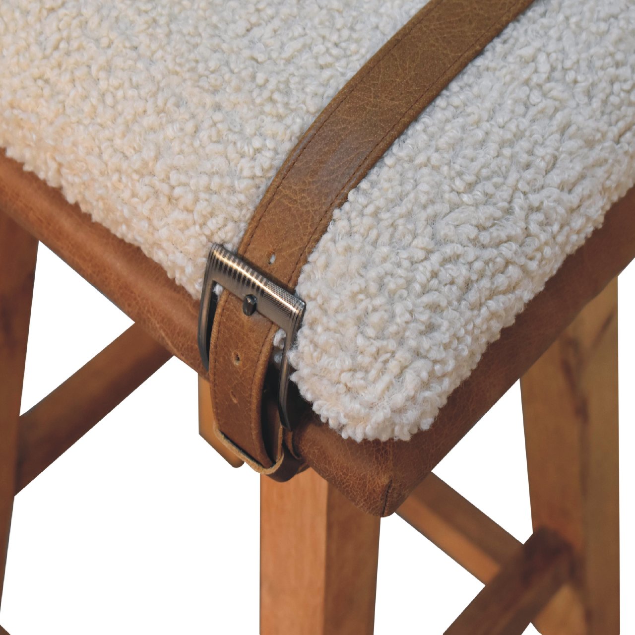 Close-up detail of the metal buckle strap and leather trim wrapped over the soft bouclé seat.