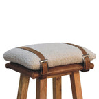Top angle view showing the leather harness straps over the cream bouclé cushion and timber frame.