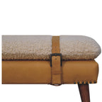 Close-up detail of the tan leather buckle strap and studded edge on the bouclé bench.
