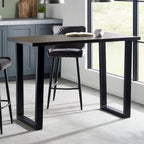 Brooklyn dark oak bar table styled with black bar stools in a modern kitchen setting.