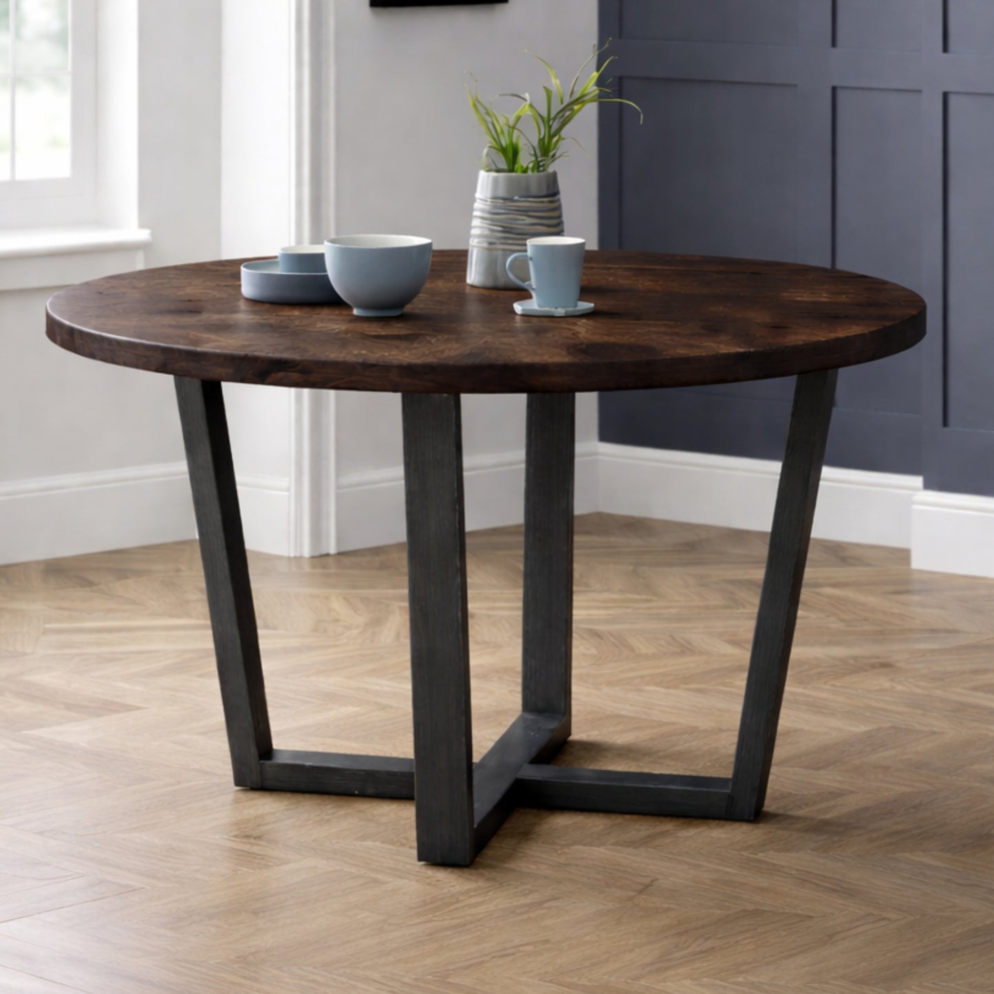Brooklyn dark oak round dining table styled with blue velvet upholstered chairs in a dining room.