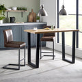 Brooklyn industrial solid oak bar table styled with brown leather bar stools in a kitchen diner setting.