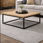 Brooklyn industrial solid oak square coffee table styled on a rug beside a modern sofa.