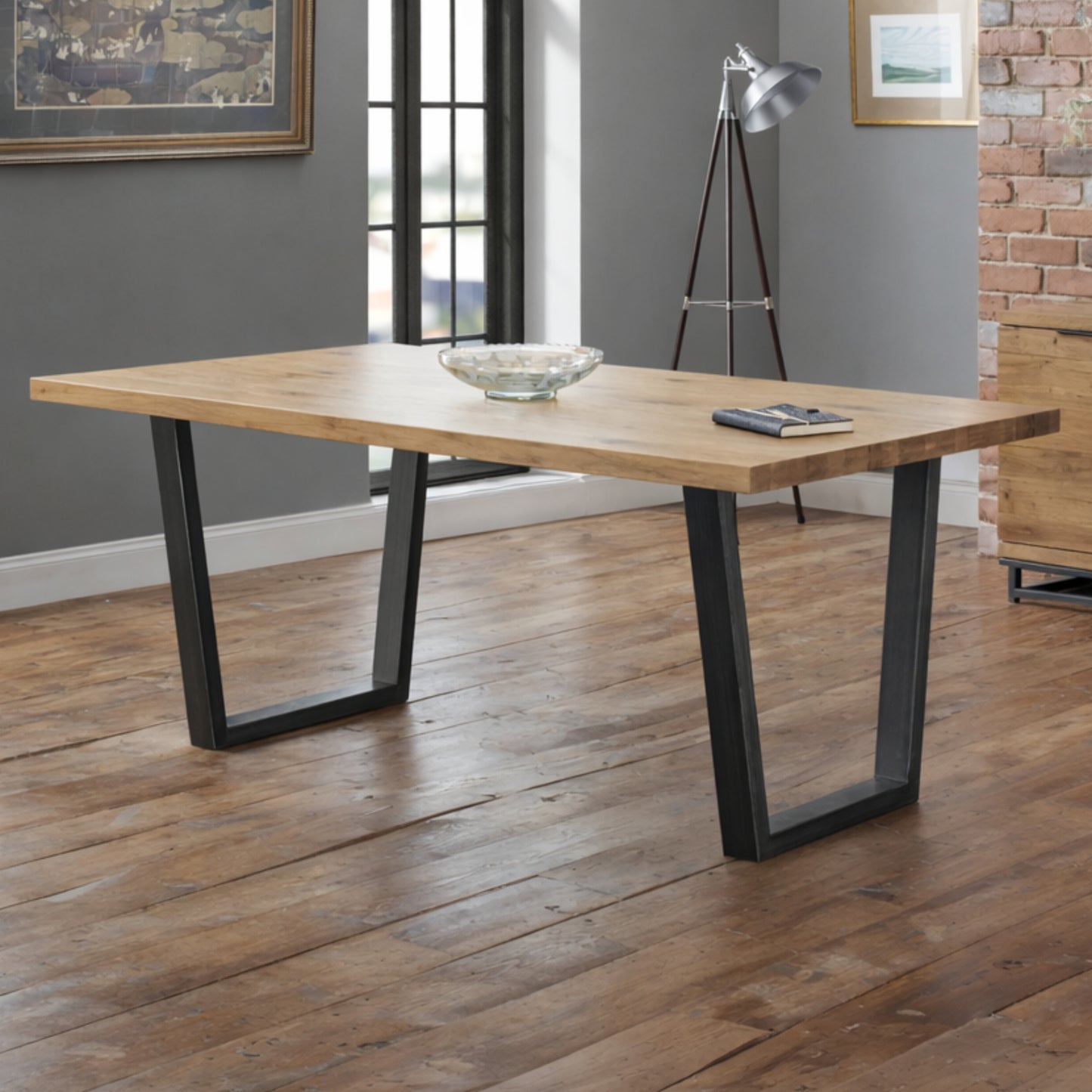 Brooklyn industrial solid oak dining table with black metal legs in a rustic dining room setting.