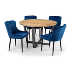 Brooklyn round oak dining table paired with four blue velvet dining chairs in a studio setup.