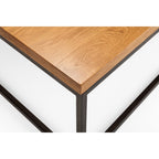Close-up detail showing the natural oak tabletop corner and black metal frame joinery.