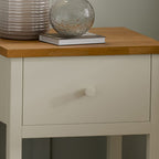 Close-up detail of the painted ivory drawer front, matching knob, and classic oak top surface.