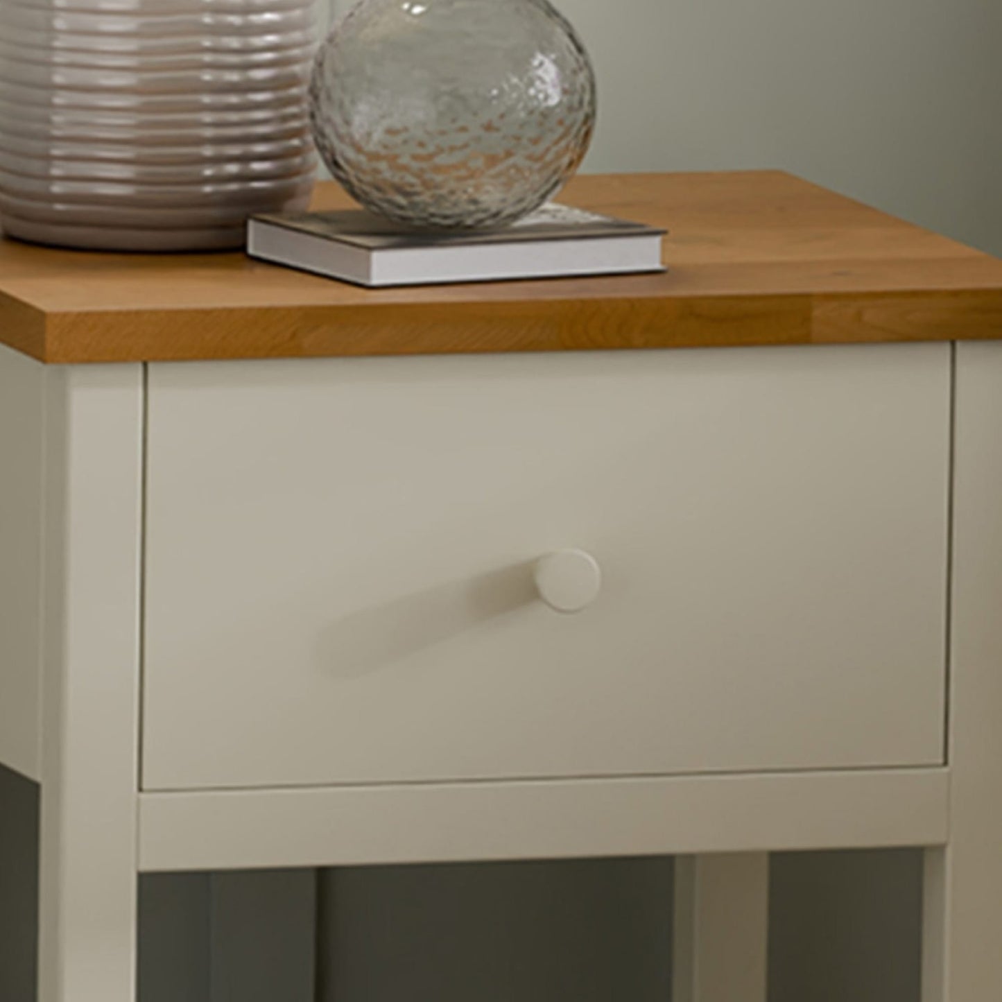 Close-up detail of the painted ivory drawer front, matching knob, and classic oak top surface.