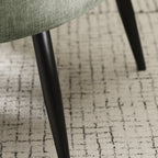 Detailed shot of the sleek, tapered black powder-coated metal legs on the Dahlia accent chair