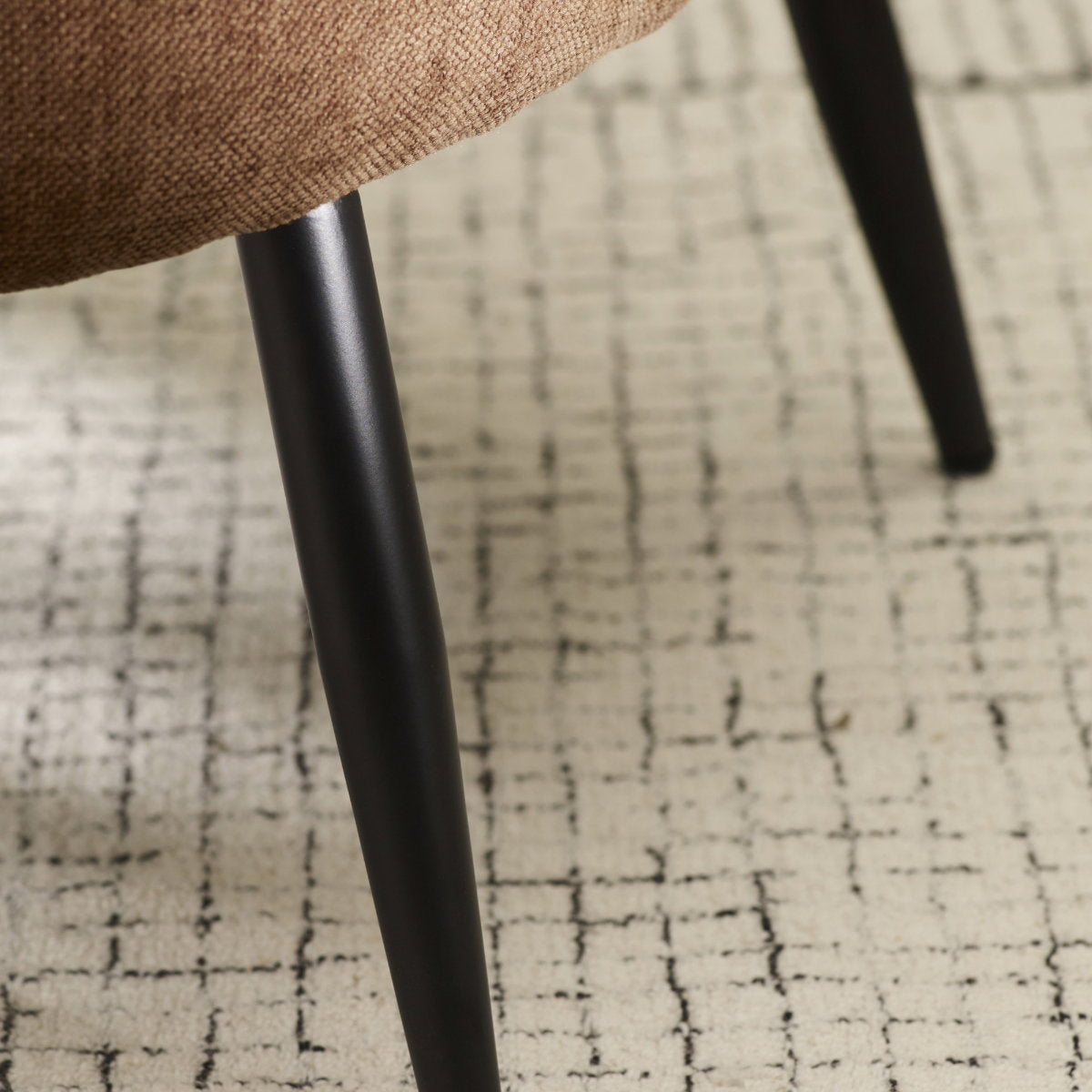 Close-up detail of the textured faux linen fabric with leg of the rust brown Dahlia accent chair