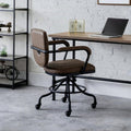 Gehry vintage brown faux leather swivel office chair styled with a wooden desk in an industrial home workspace.