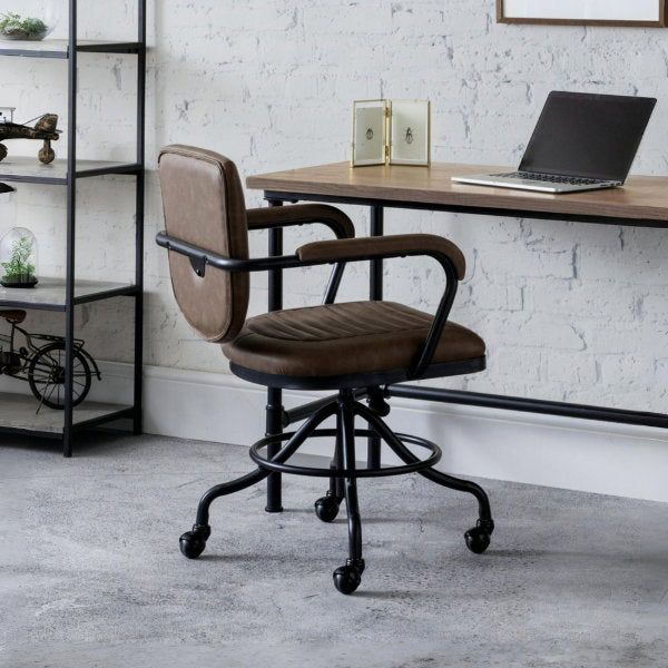 Gehry vintage brown faux leather swivel office chair styled with a wooden desk in an industrial home workspace.