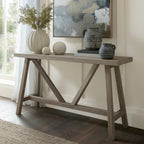 Haldon wooden trestle console table styled against a green wall with a ceramic vase, art print, and decorative jars