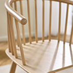 Close-up shot of the curved spindle backrest and integrated armrest detail on the Kaito oak dining chair