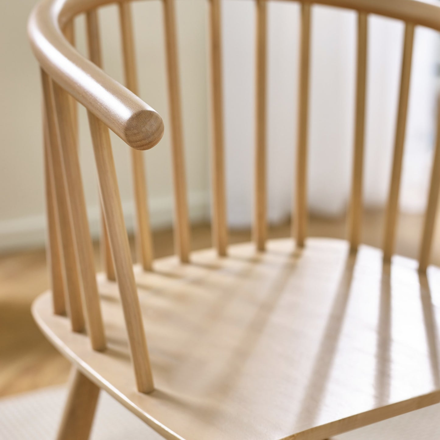 Close-up shot of the curved spindle backrest and integrated armrest detail on the Kaito oak dining chair