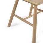 Close-up view of the splayed wooden legs and H-bar stretcher support on the Kaito oak chair