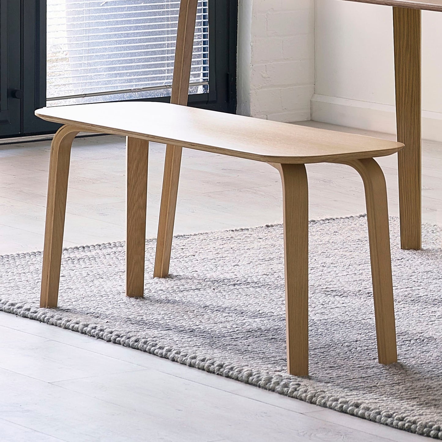 Kaito oak wooden dining bench styled beside a matching dining table on a textured rug in a bright modern home