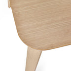 Close-up shot showing the smooth rounded corner and natural oak veneer surface of the Kaito dining table