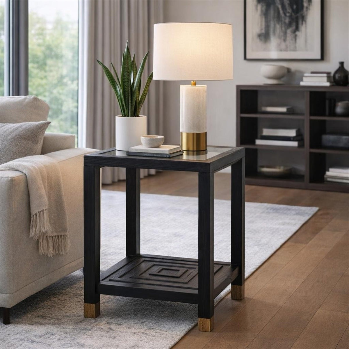 Lennox Black Side Table with glass top and brass feet styled next to a sofa with a table lamp and potted plant