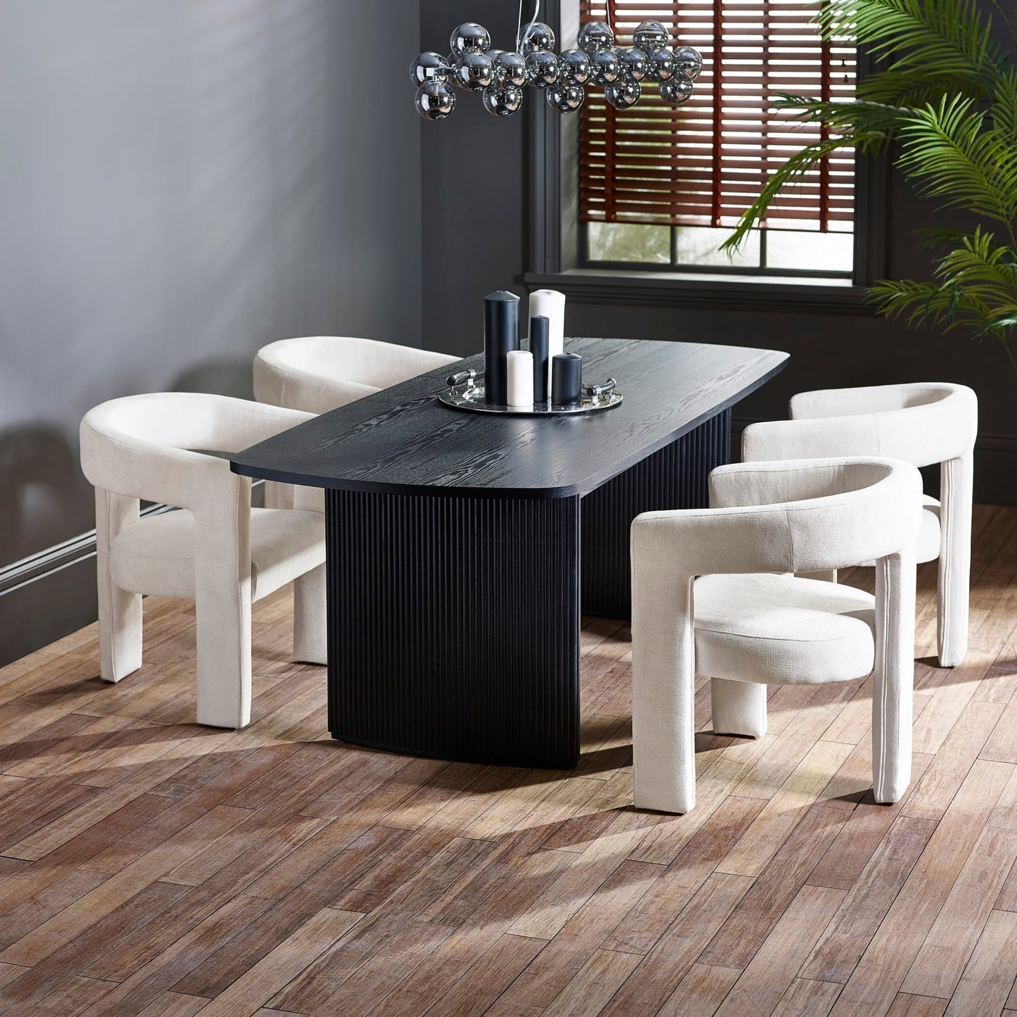 Louis black fluted extending dining table set with grey velvet armchairs and candles in a dark modern dining room