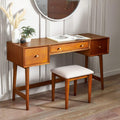 Lowry wooden dressing table and cushioned stool set styled in a modern bedroom with decorative mirror and vase.