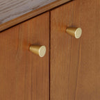 Close-up shot of the brushed gold knob hardware and rich grain of the exquisite cherry ash veneer