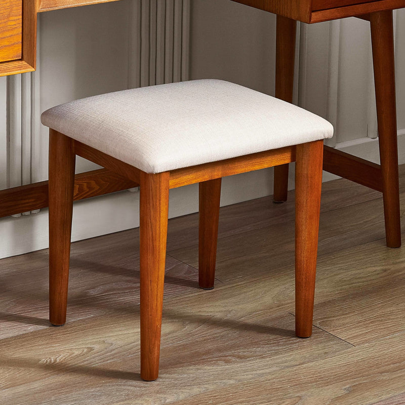 Lowry vanity stool featuring a soft neutral fabric padded cushion and sturdy wooden frame.