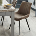 Malmo coffee brown faux leather dining chair styled next to a wooden dining table in a rustic dining room setup