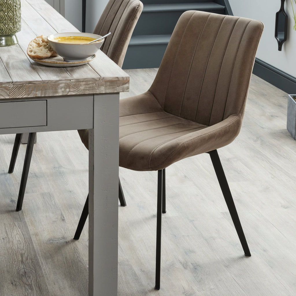 Malmo coffee brown faux leather dining chair styled next to a wooden dining table in a rustic dining room setup