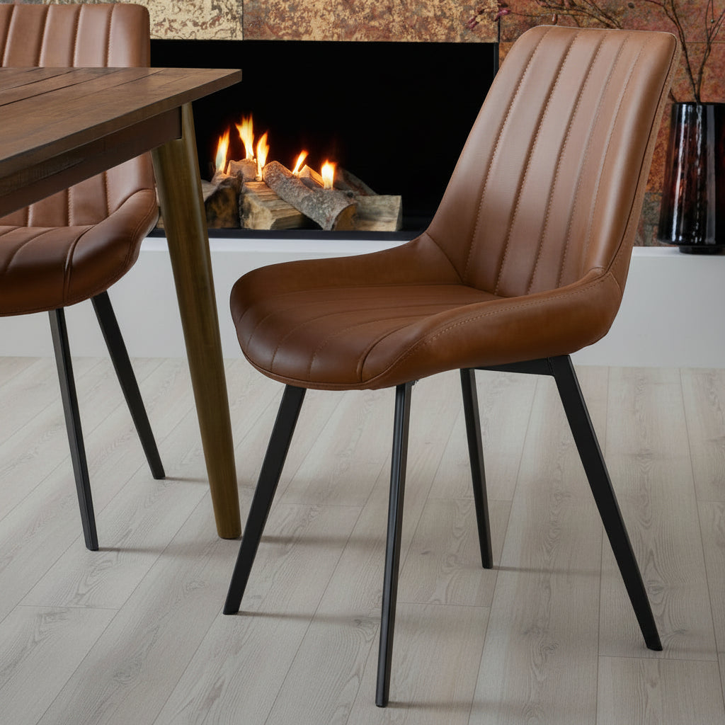 Malmo tan faux leather dining chair with channel stitching styled by a wooden dining table near a cozy fireplace