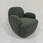Side angle perspective of the olive green Micky swivel chair highlighting smooth curved backrest   