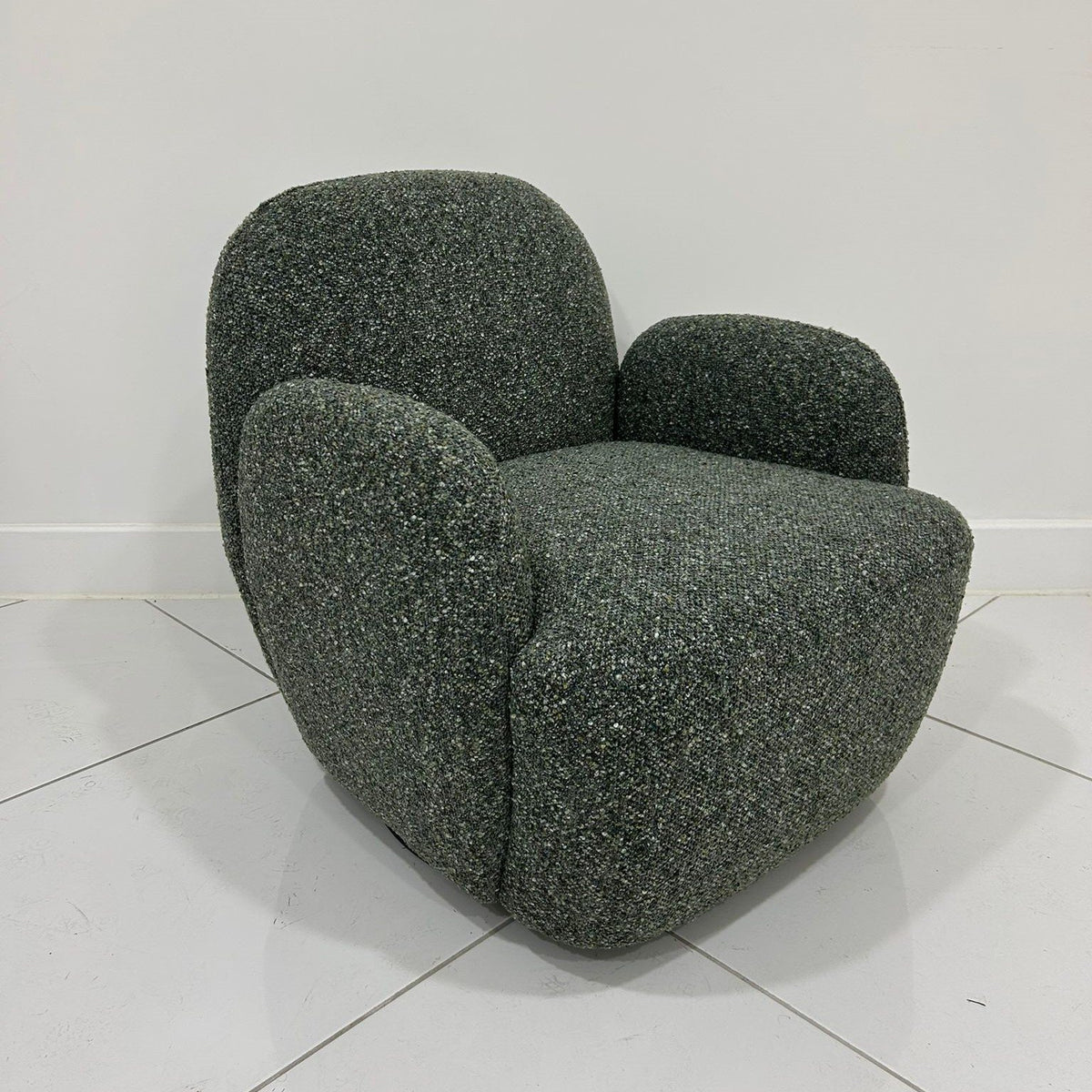 Side angle perspective of the olive green Micky swivel chair highlighting smooth curved backrest   