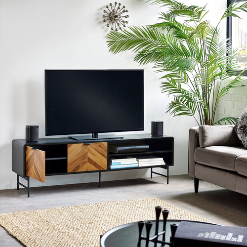 Black and wood chevron TV stand supporting a flat-screen television in a modern living room setup.