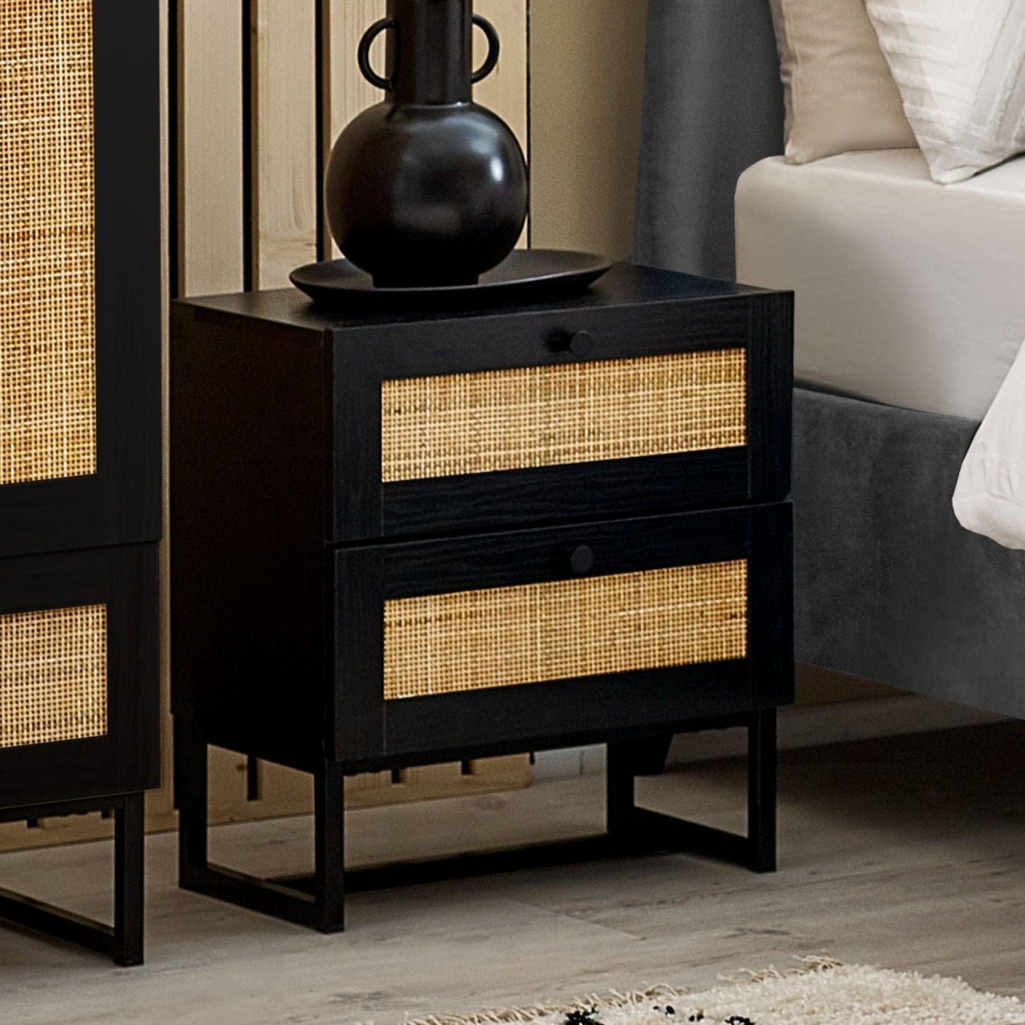 Padstow black oak 2 drawer rattan bedside table styled with vase in a bedroom setting