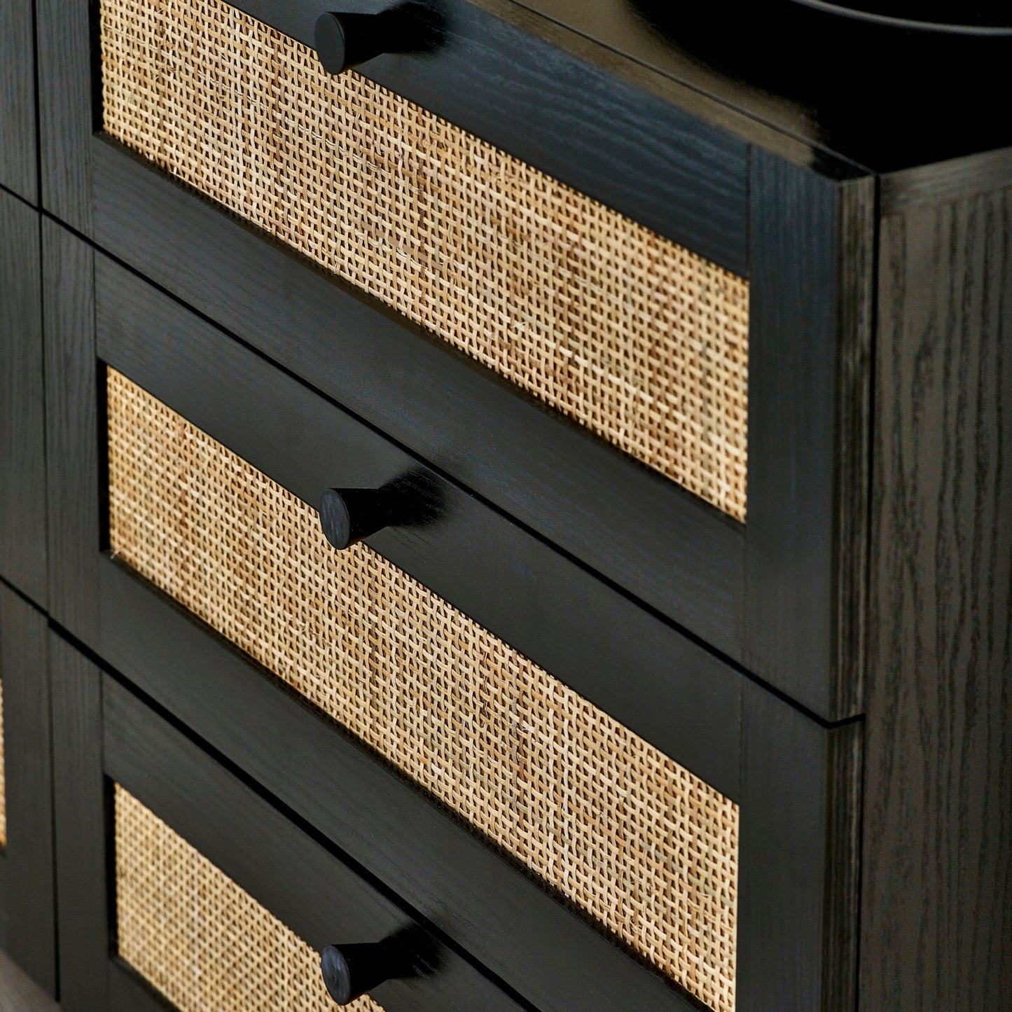 Close-up shot showing the woven cane rattan drawer details and black handles on the black oak chest