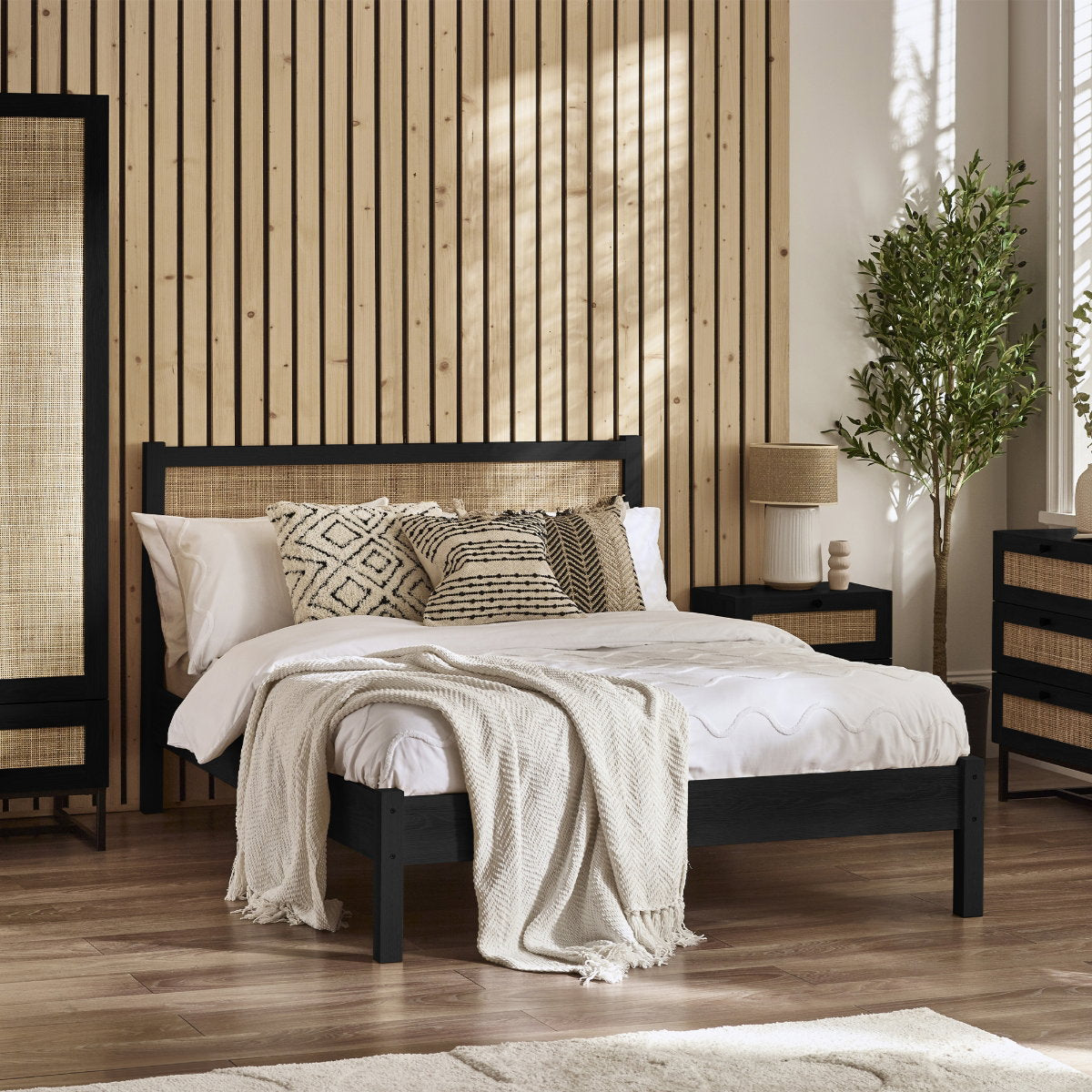 Padstow black oak wood bed frame with cane headboard in a styled bedroom
