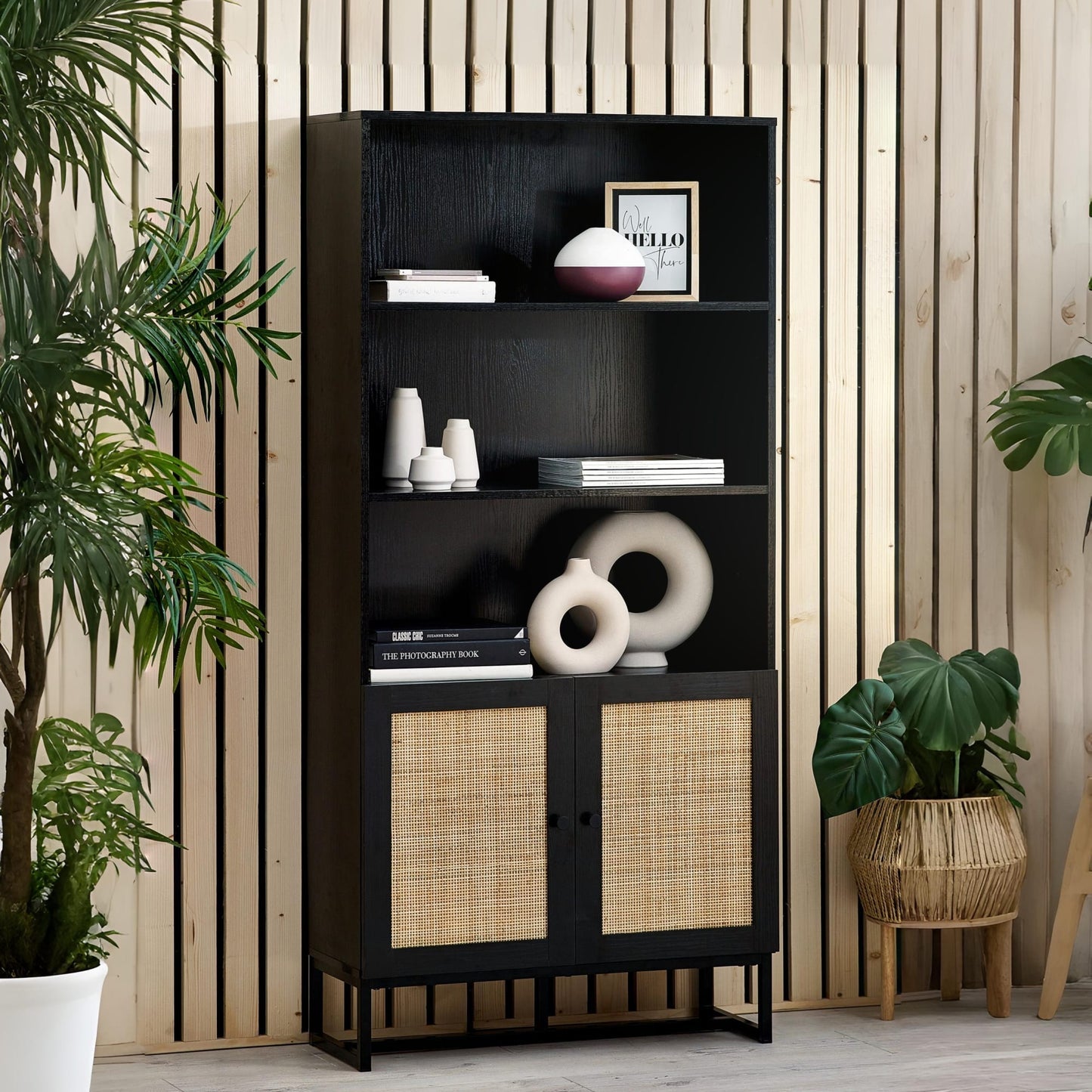 Padstow black oak tall rattan bookcase styled with books and decor in a modern interior setting