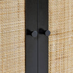Close-up of the natural cane door weave and black metal hardware on the black oak wardrobe